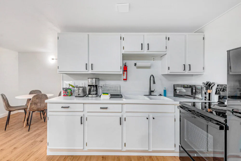Bright chalet kitchen with a stove, sink, coffee maker, and adjoining dining nook