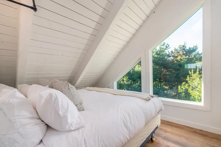 Upstairs bedroom with a window inside a Tidal House cottage