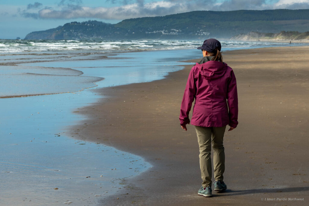 Woman in rain jacket walking along the Washington coast beach