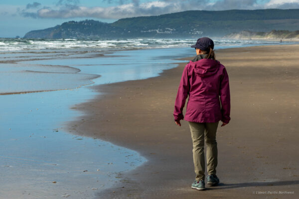 Woman in rain jacket walking along the Washington coast beach